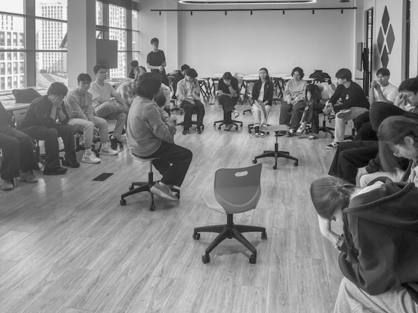 A large circle of students seated around an open floor in the middle of a game
of werewolf